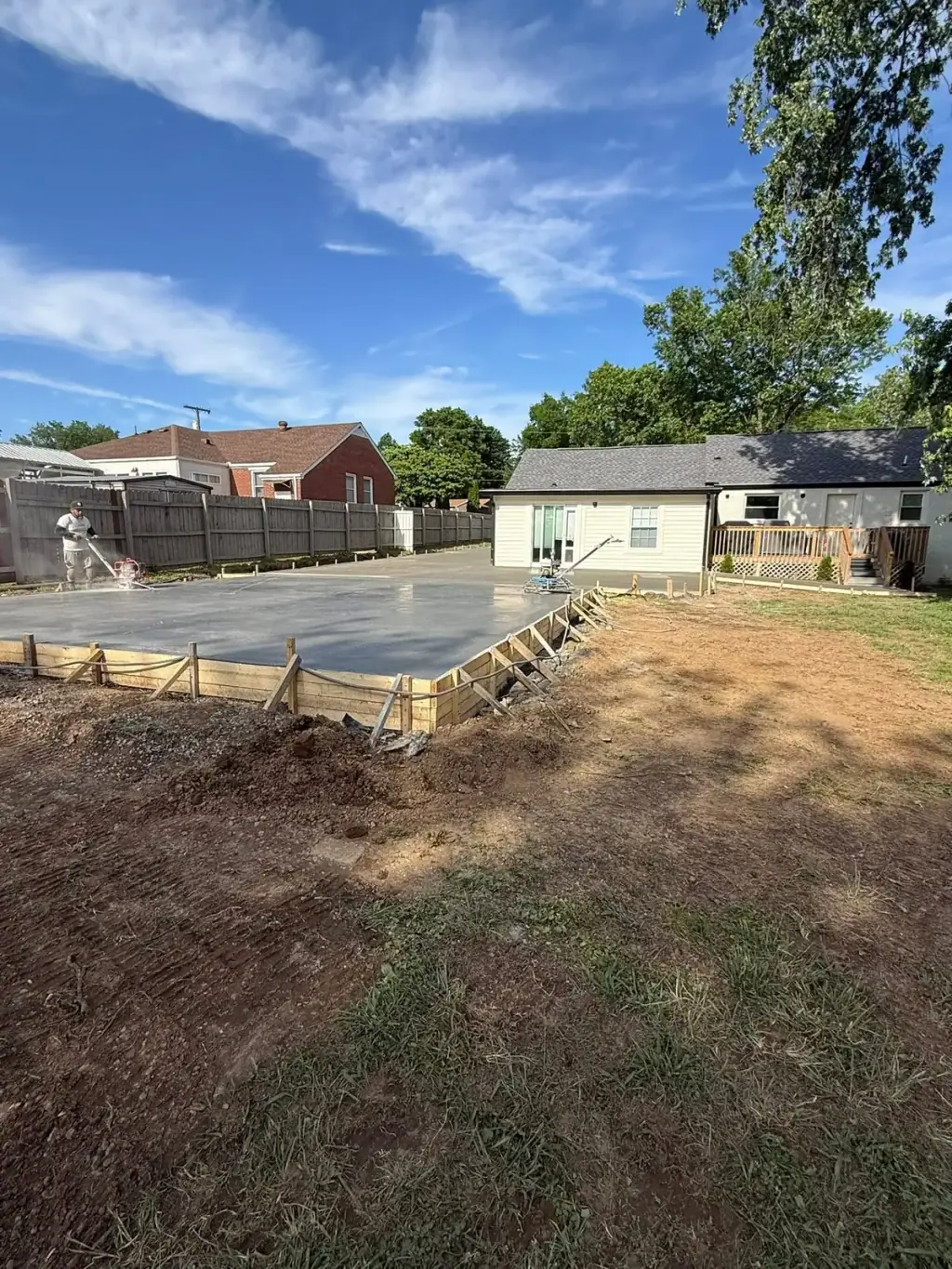 Large concrete slab poured in a back yard with the forms still set