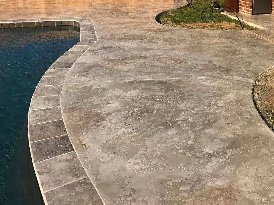 Stamped and stained concrete pool deck with a curved edge