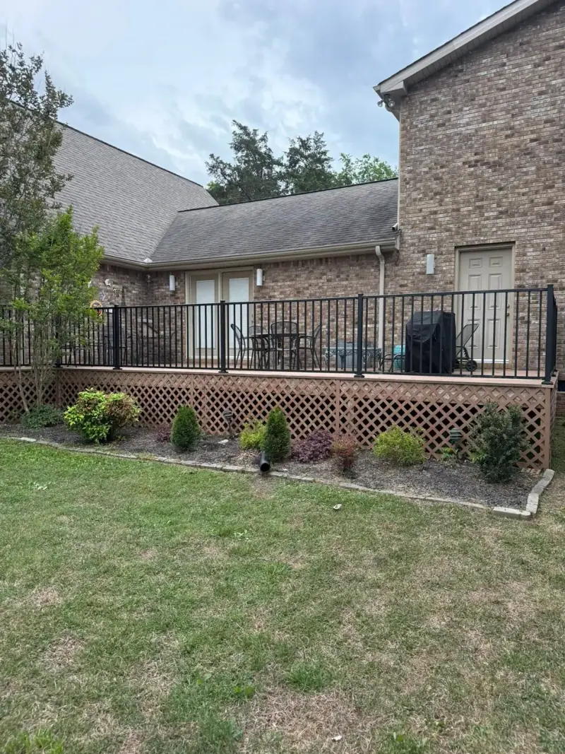 Deck with black metal railing and lattice skirting on a brick home