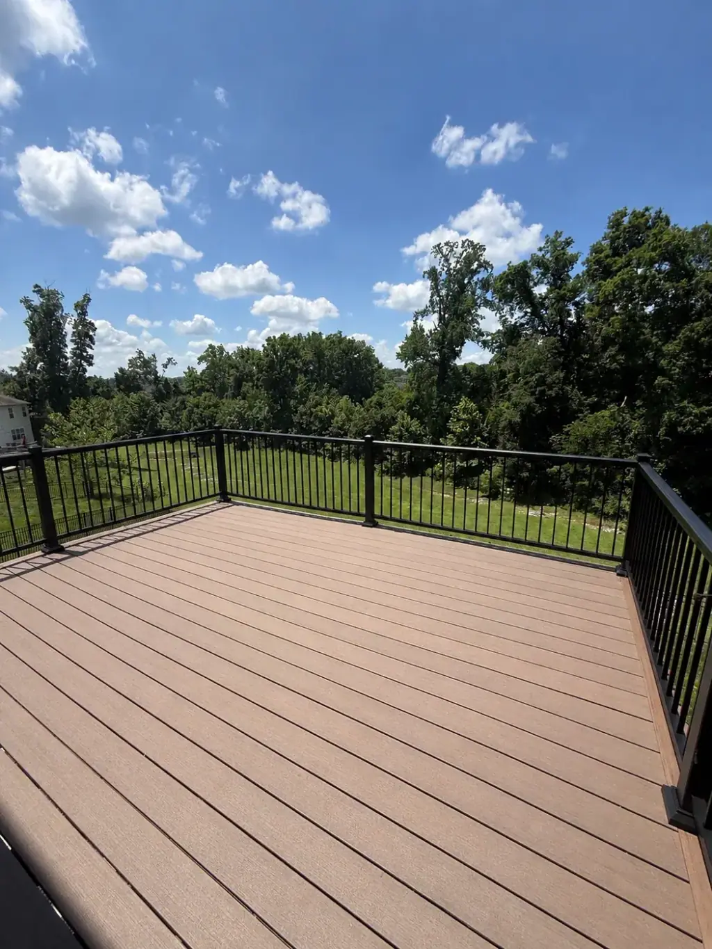 Composite deck finished with black aluminum railing looking out over the trees
