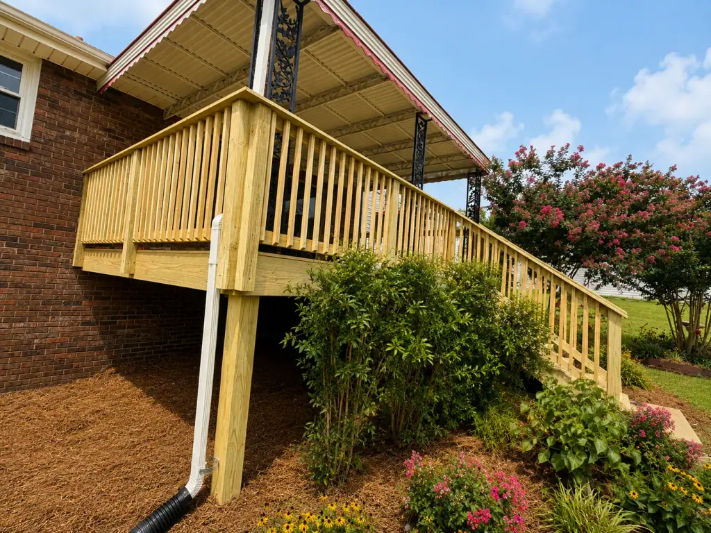 Raised wood deck along the side of a brick home with a full stair run down to grade