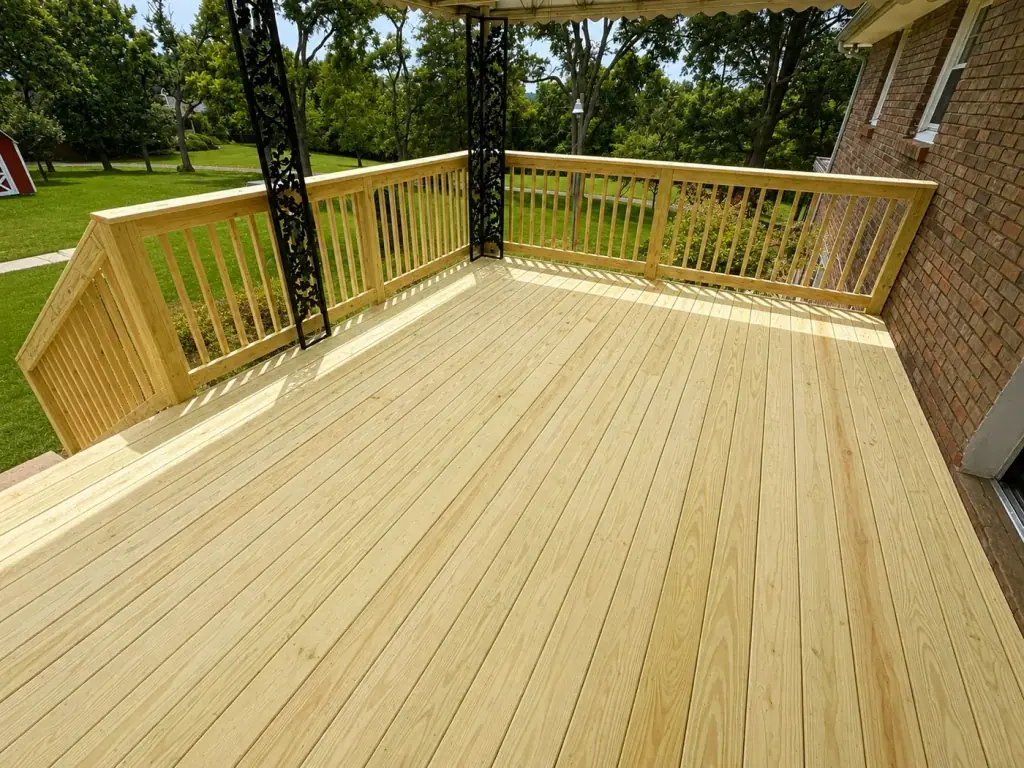 Treated wood deck with a black pergola and matching railings on a brick home