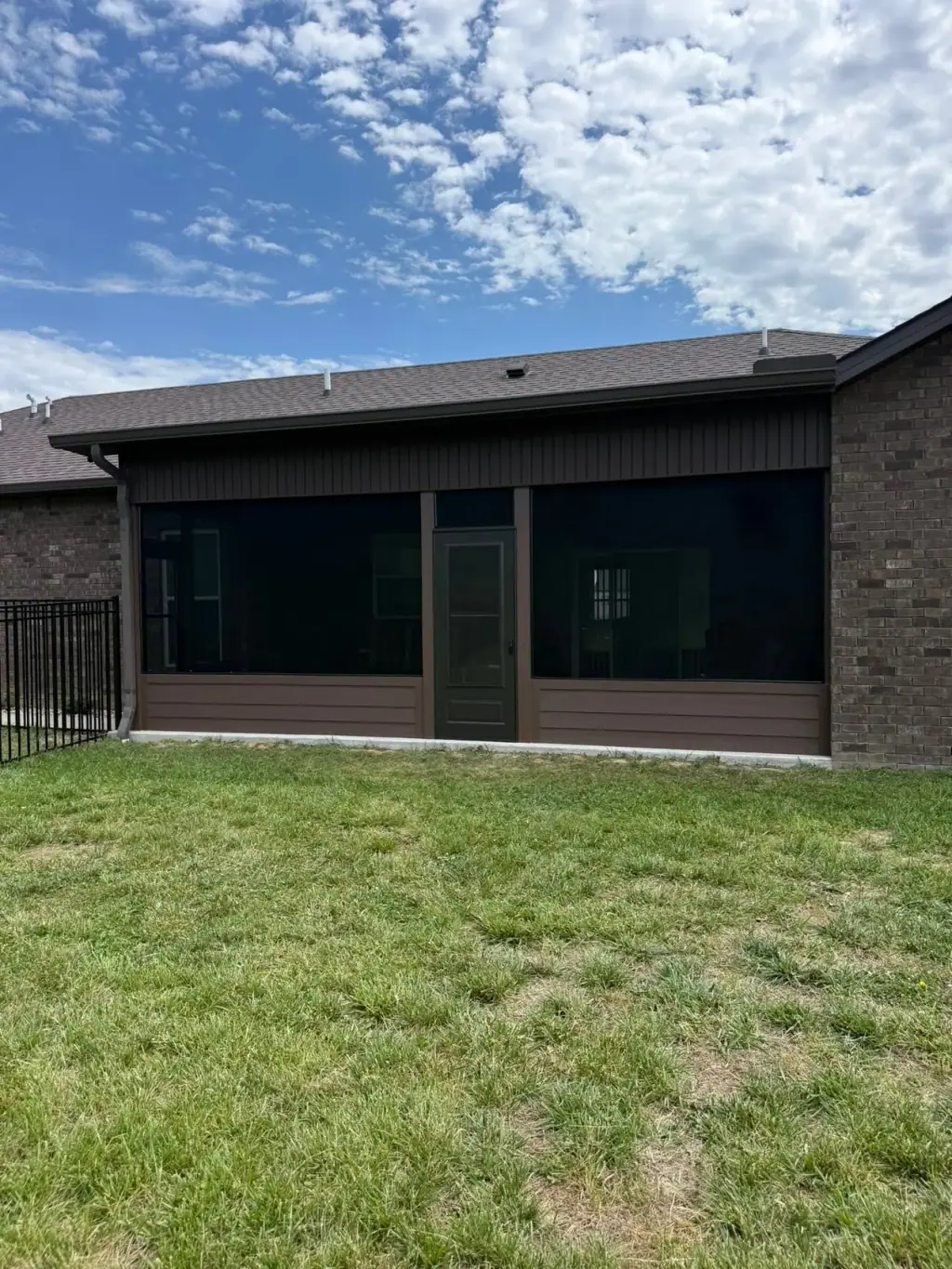 Full width screened porch across the back of a brick home