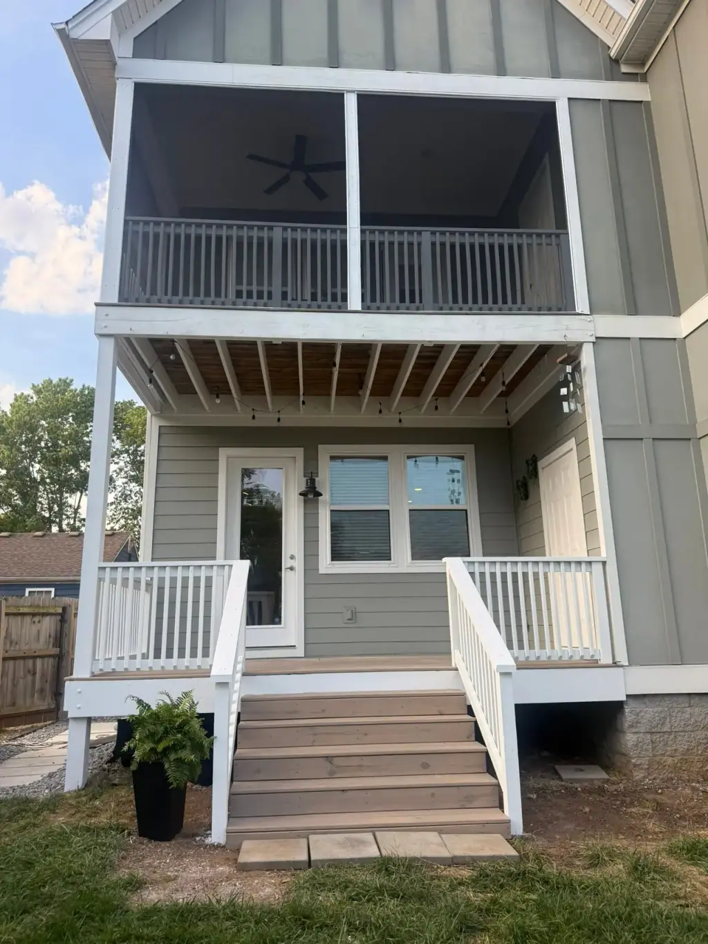 Two story screened porch and deck build with white railings and stairs