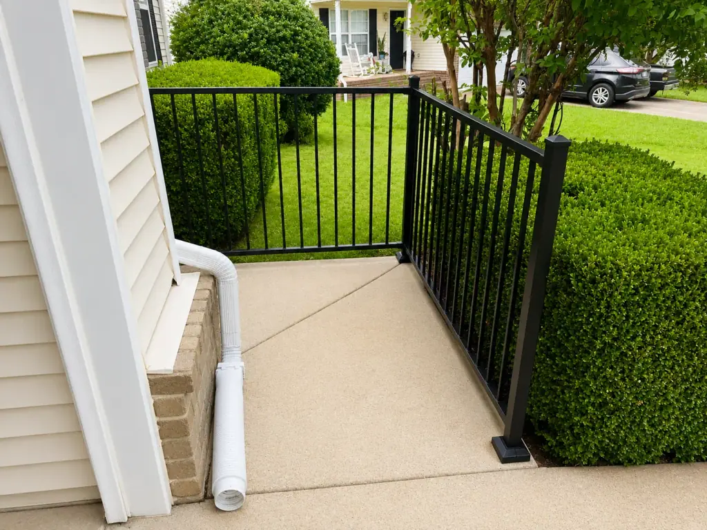 Black aluminum railing along a concrete walkway to a front entry, railing and flatwork from our general contractor Gallatin TN crew